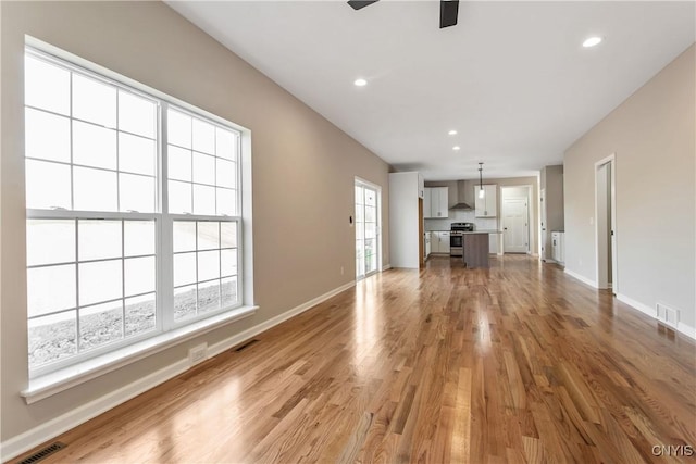 unfurnished living room featuring ceiling fan and light hardwood / wood-style flooring