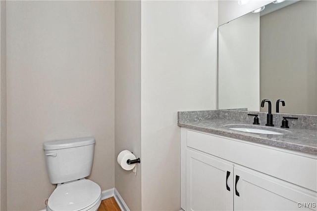 bathroom featuring wood-type flooring, toilet, and vanity