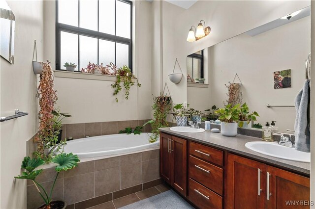 bathroom with vanity, a relaxing tiled tub, and tile patterned flooring