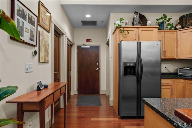 kitchen featuring light brown cabinets, stainless steel fridge, dark hardwood / wood-style flooring, and dark stone countertops