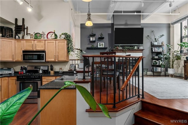 kitchen featuring sink, dark stone countertops, hanging light fixtures, and stainless steel appliances