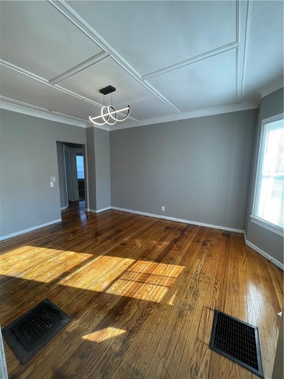 unfurnished room with wood-type flooring, a notable chandelier, and crown molding