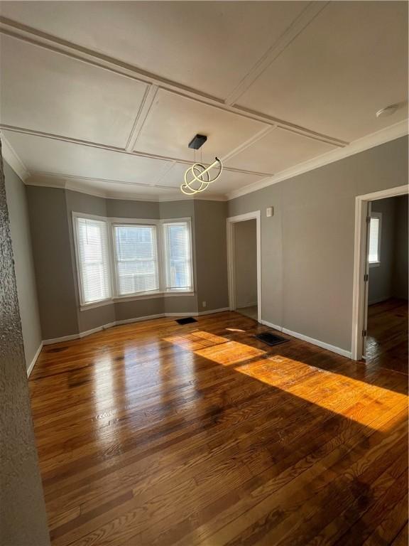 unfurnished room featuring coffered ceiling, crown molding, and dark wood-type flooring