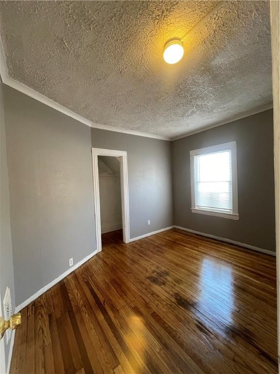 spare room featuring wood-type flooring, ornamental molding, and a textured ceiling