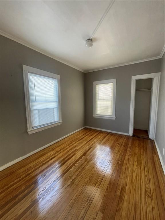 unfurnished bedroom featuring wood-type flooring, a closet, and crown molding