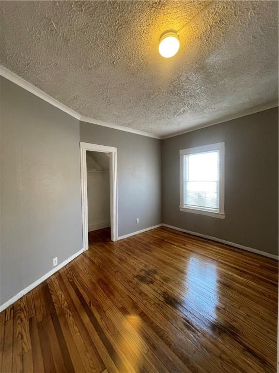 spare room featuring hardwood / wood-style flooring, a textured ceiling, and ornamental molding