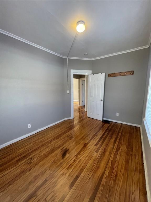 empty room featuring ornamental molding and wood-type flooring