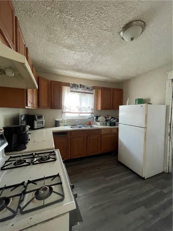 kitchen featuring sink, white appliances, dark hardwood / wood-style floors, and a textured ceiling