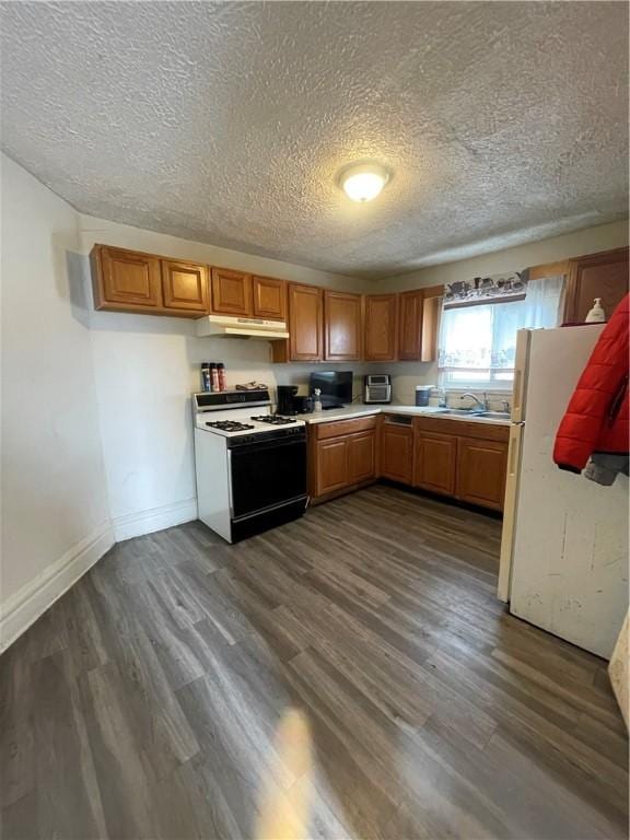 kitchen featuring sink, white appliances, a textured ceiling, and dark hardwood / wood-style flooring