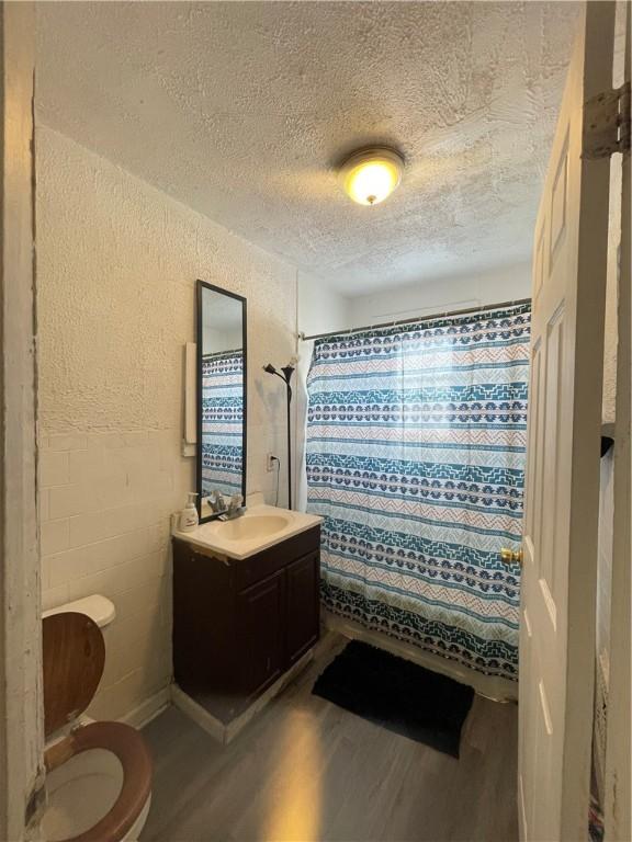 bathroom with hardwood / wood-style floors, toilet, vanity, and a shower with shower curtain