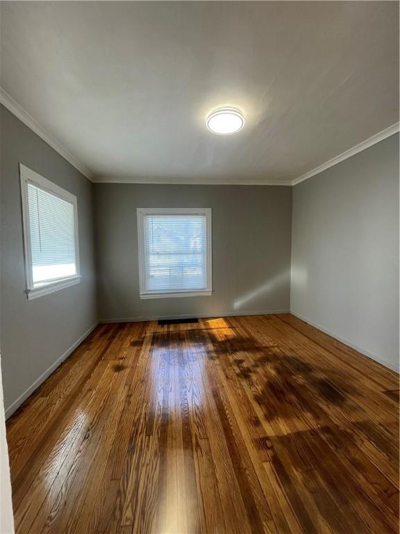 unfurnished room with ornamental molding and hardwood / wood-style floors