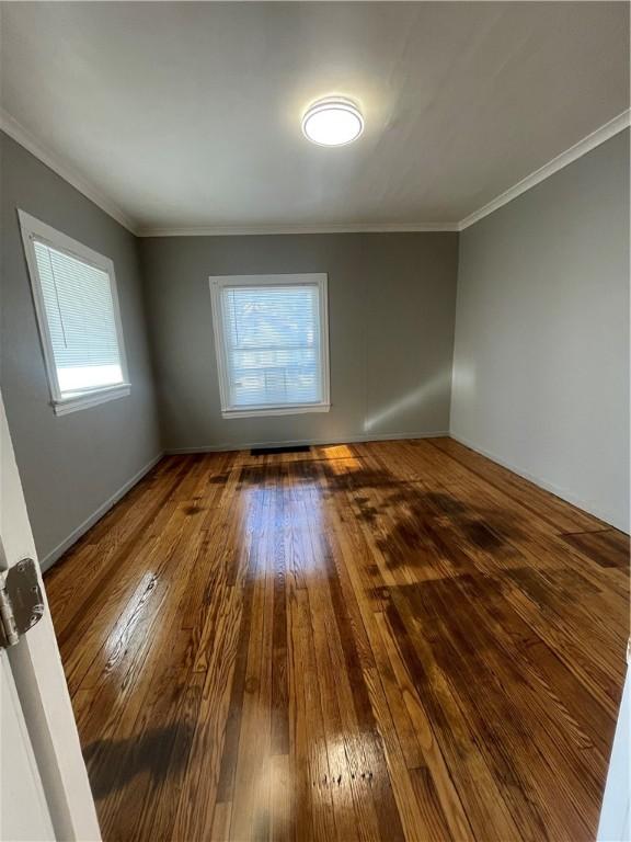 empty room featuring a wealth of natural light, hardwood / wood-style floors, and crown molding