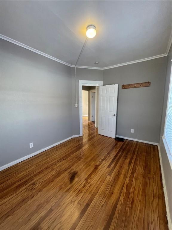 empty room featuring wood-type flooring and crown molding