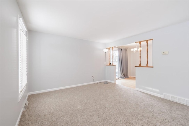 spare room with light colored carpet and a chandelier