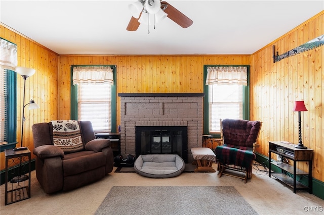 carpeted living room with ceiling fan, wood walls, plenty of natural light, and a fireplace