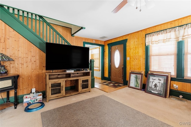 carpeted living room with wooden walls and ceiling fan