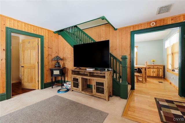 carpeted living room featuring wooden walls