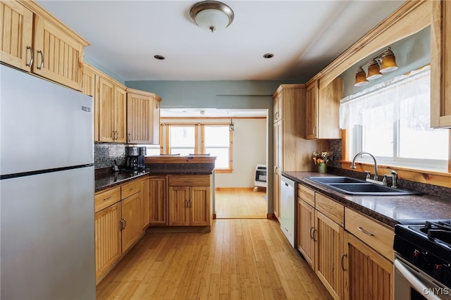 kitchen featuring appliances with stainless steel finishes, light hardwood / wood-style floors, sink, backsplash, and heating unit