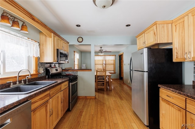 kitchen with light brown cabinets, stainless steel appliances, light hardwood / wood-style floors, sink, and ceiling fan