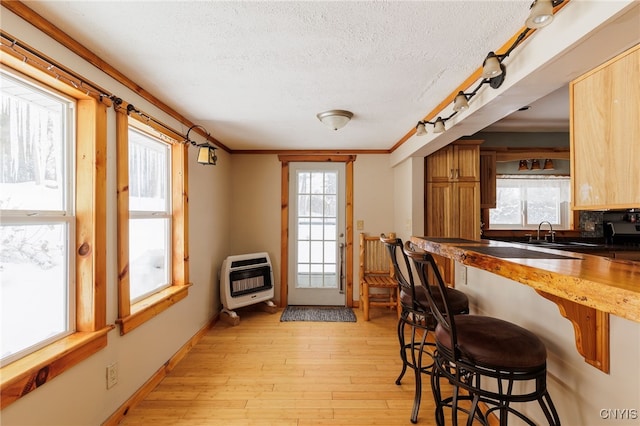 kitchen with crown molding, light hardwood / wood-style flooring, sink, a textured ceiling, and heating unit