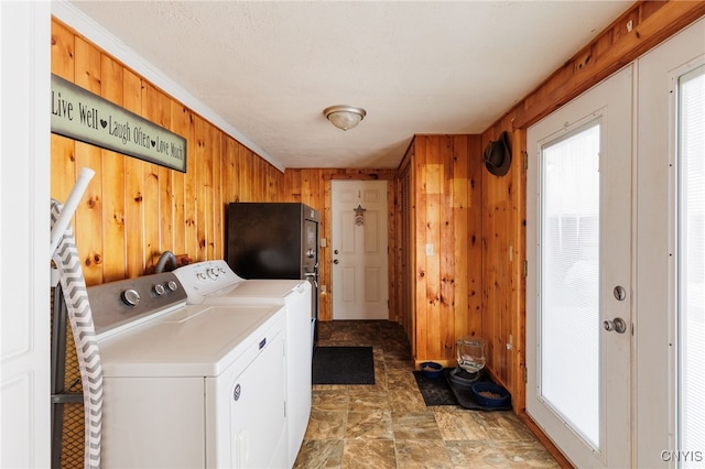 clothes washing area with wooden walls and independent washer and dryer