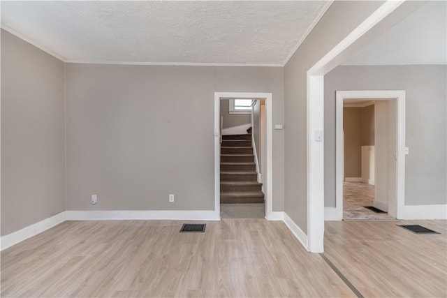 unfurnished room with crown molding, a textured ceiling, and light hardwood / wood-style flooring