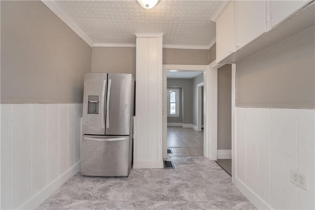 kitchen featuring white cabinets, ornamental molding, and stainless steel refrigerator with ice dispenser