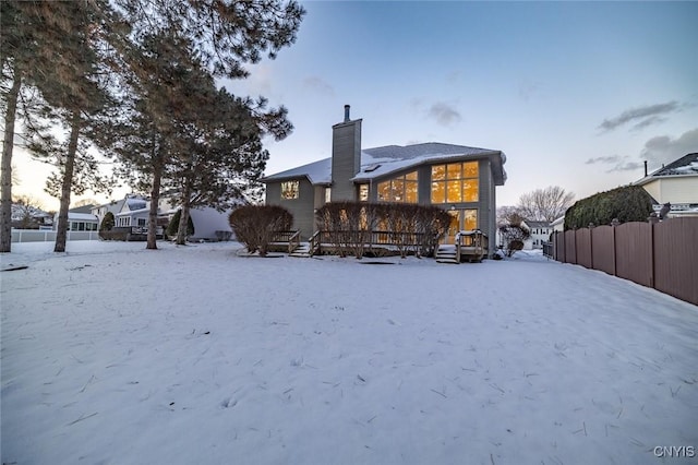 snow covered rear of property featuring a deck