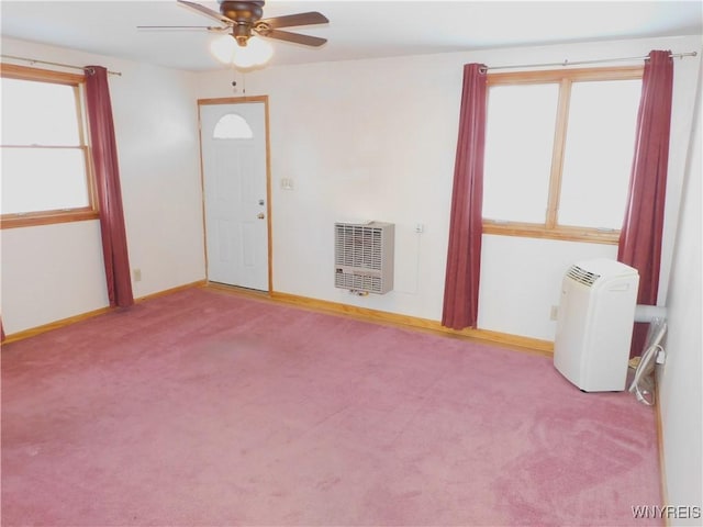 empty room with light carpet, heating unit, and ceiling fan