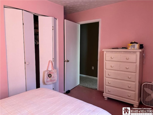 bedroom with dark colored carpet, a textured ceiling, and a closet