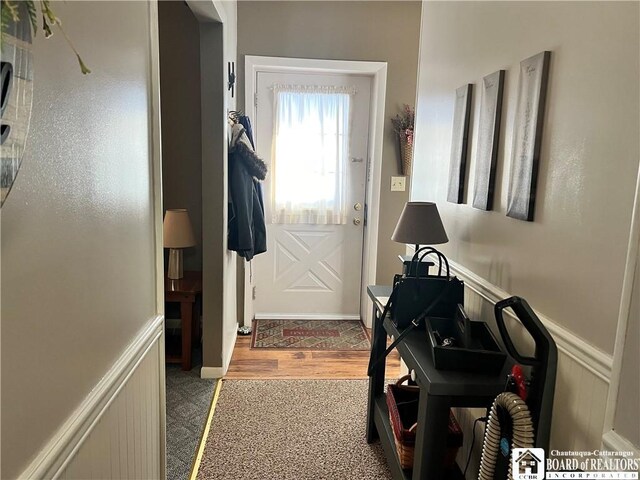 entryway featuring wainscoting, wood finished floors, and a decorative wall