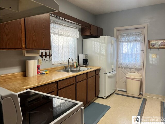 kitchen with sink, white fridge, dark brown cabinetry, and range