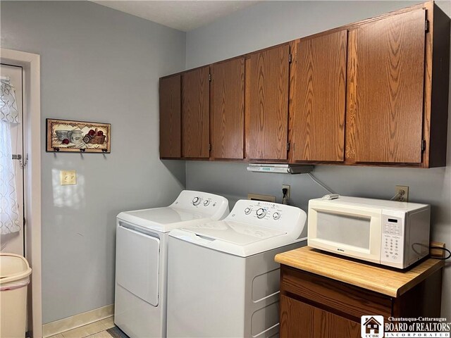 laundry area with independent washer and dryer, cabinets, and light tile patterned floors