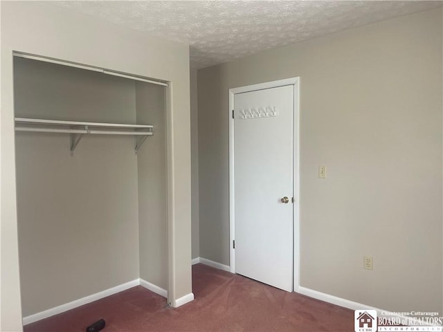 unfurnished bedroom featuring carpet floors, a closet, a textured ceiling, and baseboards