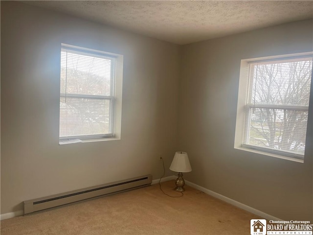 carpeted empty room with a textured ceiling, a baseboard radiator, and baseboards