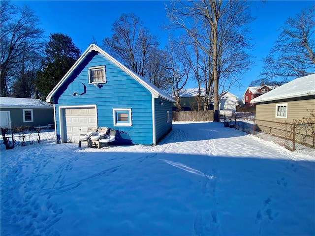 snow covered property featuring a garage and an outdoor structure