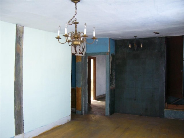 unfurnished room featuring dark wood-type flooring and a notable chandelier