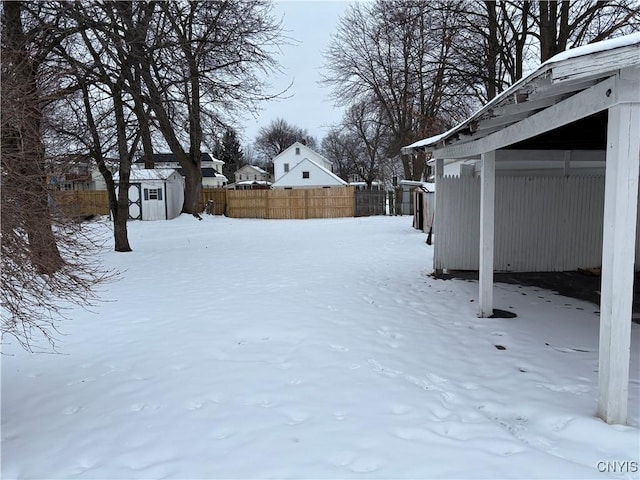 snowy yard featuring a storage unit