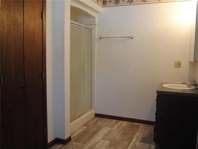 bathroom with hardwood / wood-style floors, walk in shower, and vanity