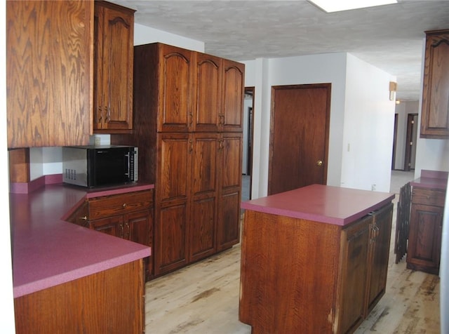 kitchen with a textured ceiling, light hardwood / wood-style flooring, and a center island