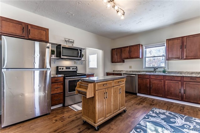 kitchen with sink, a textured ceiling, dark hardwood / wood-style floors, and stainless steel appliances