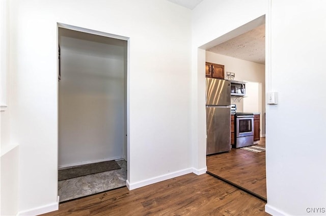 interior space featuring wood-type flooring, a textured ceiling, and appliances with stainless steel finishes