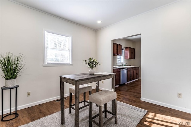 dining area with a healthy amount of sunlight, ornamental molding, and dark hardwood / wood-style floors