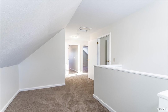 corridor with carpet flooring, a textured ceiling, and lofted ceiling