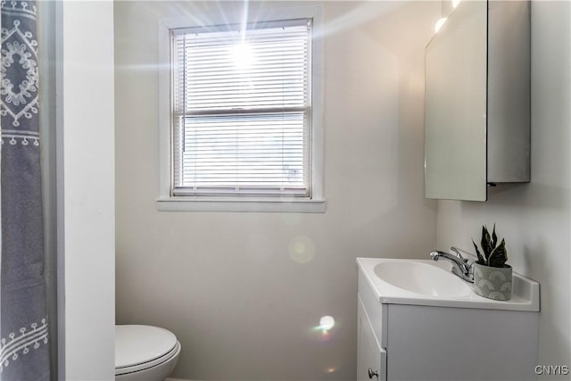 bathroom featuring a wealth of natural light, toilet, and vanity