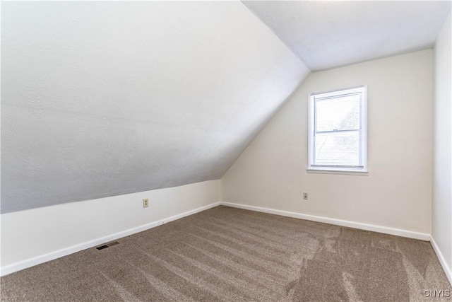 bonus room with carpet, lofted ceiling, and a textured ceiling