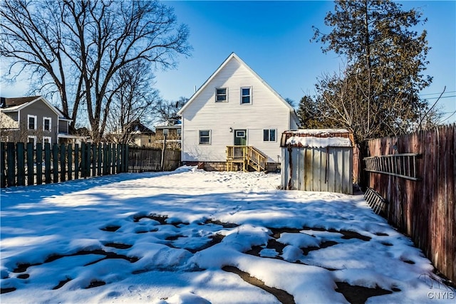 snow covered rear of property with a storage unit