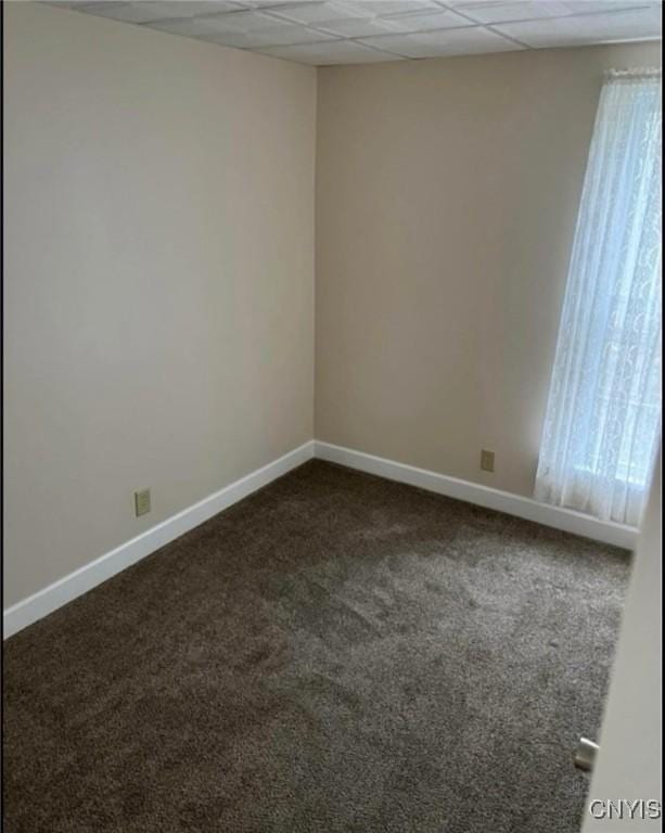 unfurnished room featuring dark carpet and a paneled ceiling