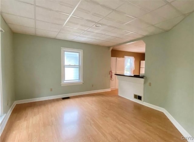 unfurnished living room with a paneled ceiling and light hardwood / wood-style floors