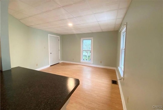 unfurnished room featuring light hardwood / wood-style flooring and a drop ceiling